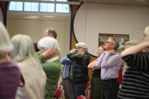 Choir members warming up during choral choir rehearsal, Birmingham UK